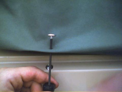 1994 Ford Bronco - A hand is shown securing a soft top attachment point with a tool.