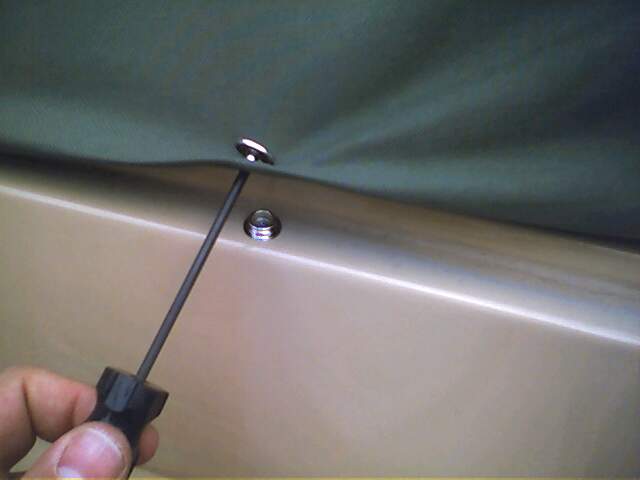 Tan vehicle body with dark green soft top being attached by a screwdriver to a silver stud