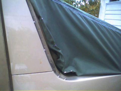 1994 Ford Bronco - Close-up view of the attachment points for a dark green soft top on a tan vehicle.