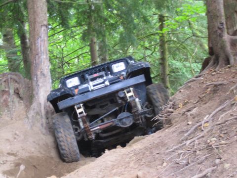 1990 Ford Bronco - Jeep Wrangler tackling an off-road trail, showing its suspension and tires on the challenging terrain.