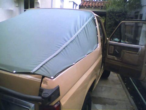 1994 Ford Bronco - This vehicle has a soft top covering the bed, with the driver's door open.