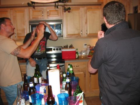 1985 Ford LTD Crown Victoria - A party scene unfolds in a kitchen with people interacting around a counter filled with drinks.