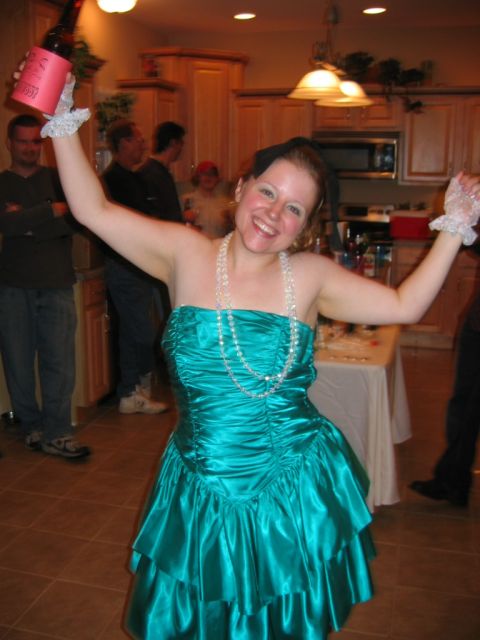 1985 Ford LTD Crown Victoria - A woman in a teal dress celebrates at a party, holding a bottle aloft.