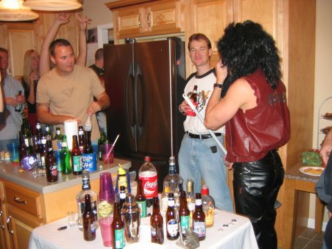 1985 Ford LTD Crown Victoria - A group of people are gathered in a kitchen, with drinks spread across the counter and a table.