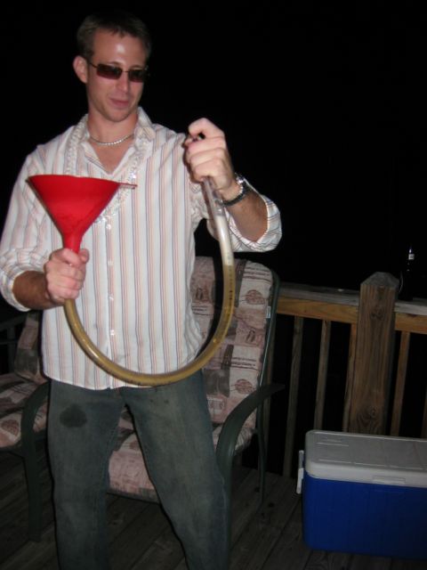 1985 Ford LTD Crown Victoria - A man prepares to use a beer funnel on a deck at night.