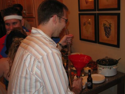 1985 Ford LTD Crown Victoria - A group of people are gathered at a party, with one individual actively preparing drinks using a funnel.