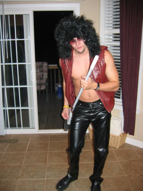 1985 Ford LTD Crown Victoria - Man in a costume with a wig, vest, and leather pants poses indoors.