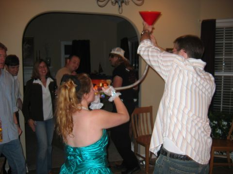 1985 Ford LTD Crown Victoria - A group of people are enjoying a party, with one individual pouring a beverage using a funnel and tube.