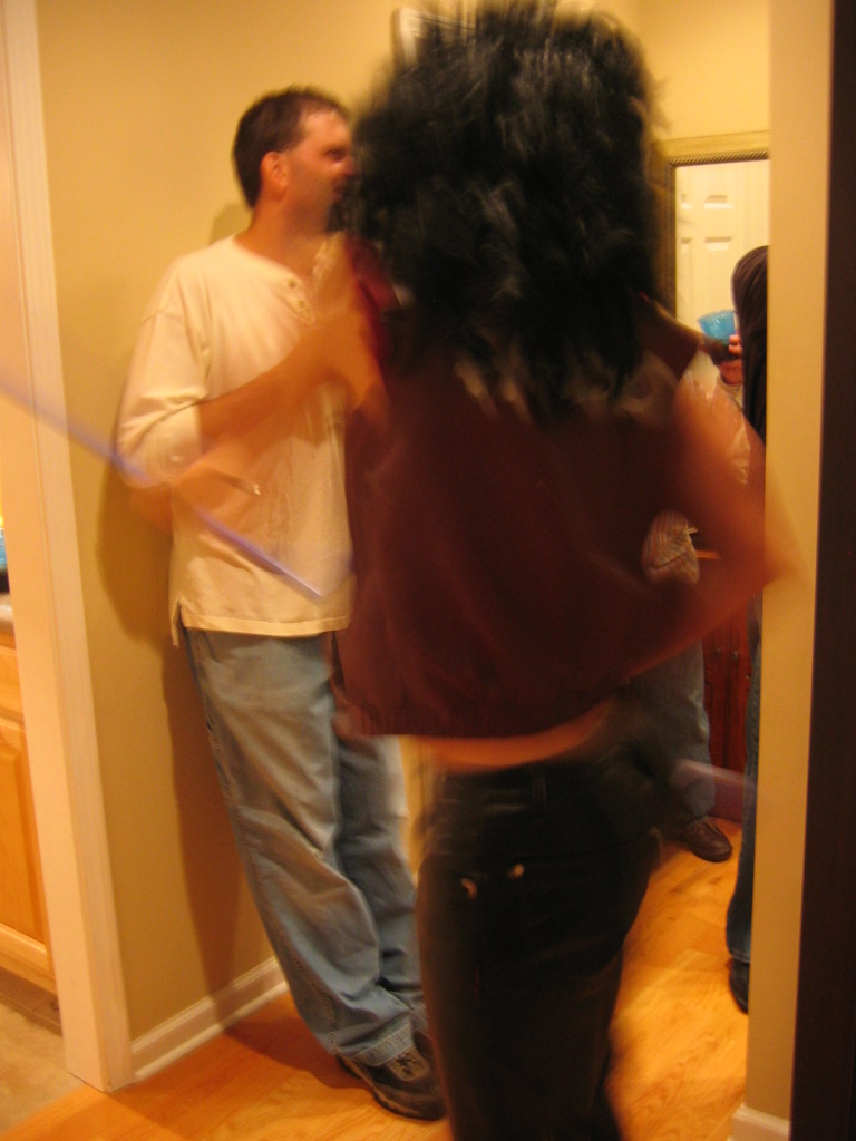 People in a hallway during a party, one person is wearing a wig