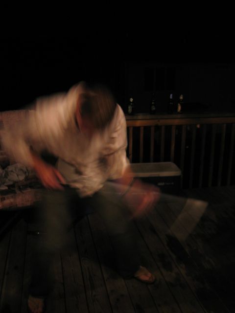 1985 Ford LTD Crown Victoria - A person is captured in motion on a wooden deck at night, with bottles visible on the railing.