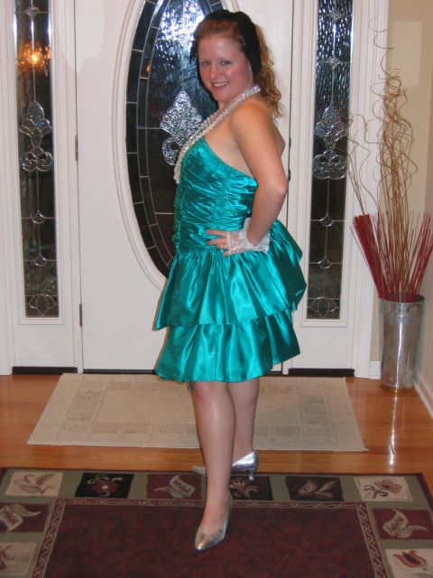 1985 Ford LTD Crown Victoria - A woman in a teal, ruffled dress and pearls poses in front of a decorated doorway.