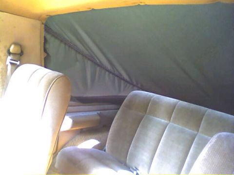1994 Ford Bronco - Interior view shows tan cloth seats and a dark soft top, with a seatbelt visible.
