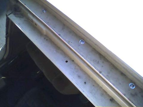 1994 Ford Bronco - Detail of a vehicle's body panel showing trim and screw attachments.