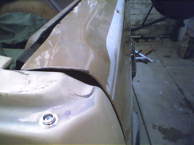 Tan car body panel with a silver bolt, showing damage and repair marks