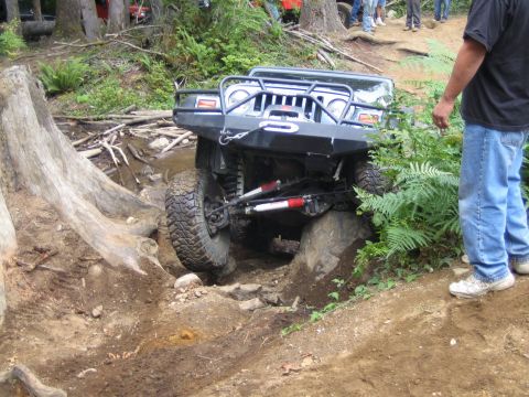 1990 Ford Bronco - This modified Jeep Wrangler navigates a challenging off-road obstacle course with large rocks and fallen trees.