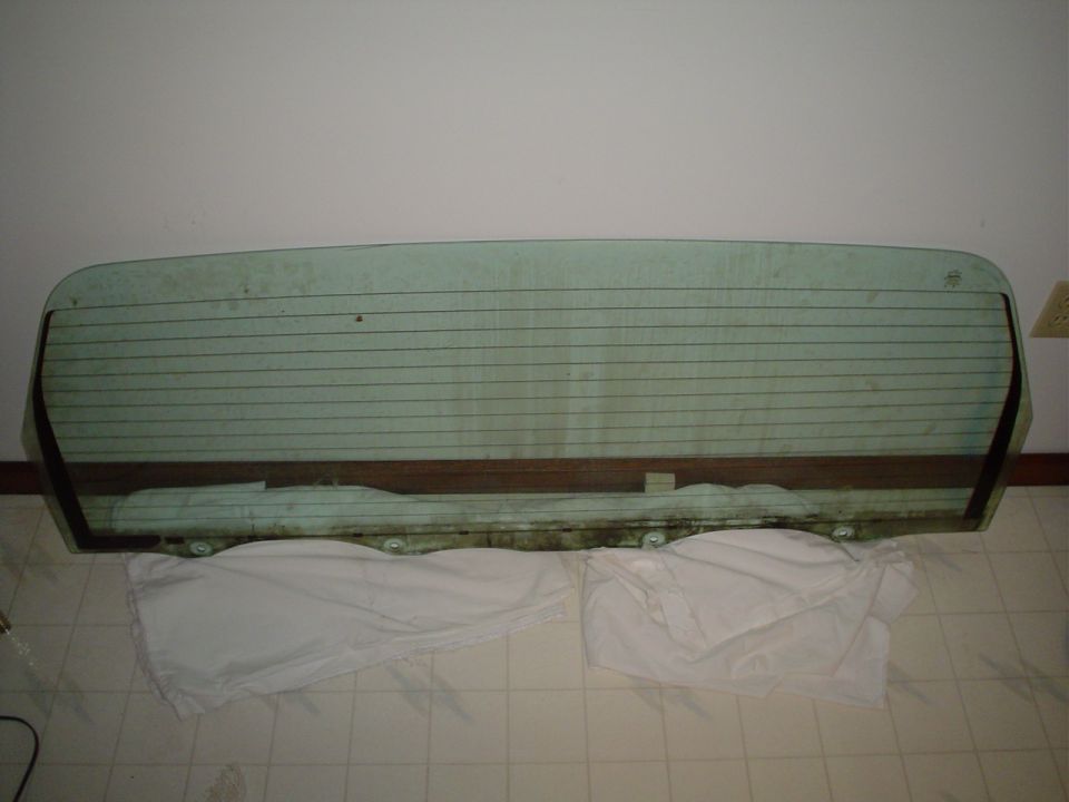 Rear window glass with defroster lines and brown trim