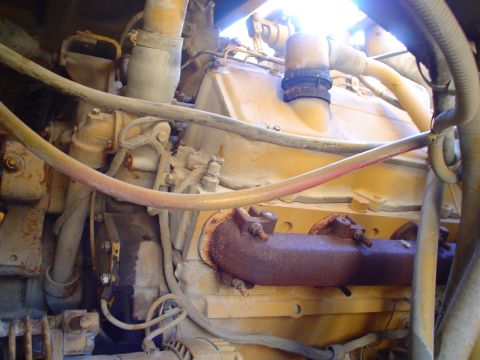 1966 International School Bus - This image shows a close-up view of an engine, likely from a heavy-duty vehicle, with visible hoses and rusty exhaust components.