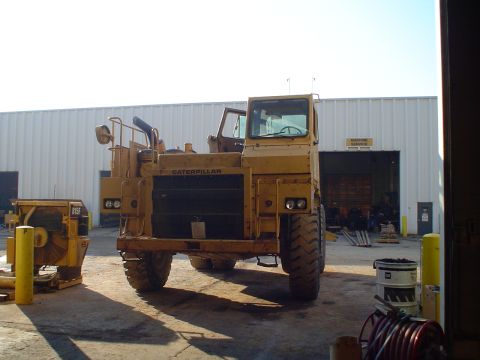 1966 International School Bus - Caterpillar articulated dump truck and other equipment outside a service building.