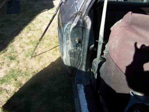 1978 Ford Mustang II - Interior view of a car door held open by a prop rod, revealing the seat and seatbelt.