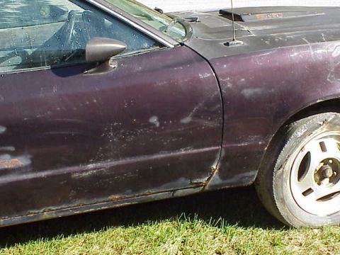 1978 Ford Mustang II - A close-up side view of a damaged purple car door and fender, showing significant rust.