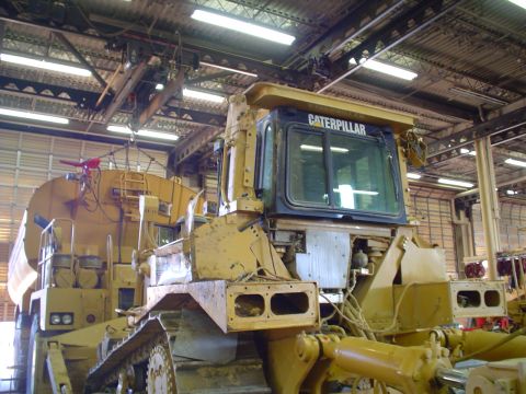 1966 International School Bus - A yellow Caterpillar bulldozer is shown in a workshop, with 'CATERPILLAR' visible on the cab.