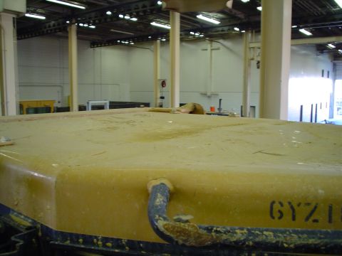 1966 International School Bus - The top of a yellow vehicle, possibly under repair or in storage, shows some stenciled markings and a pipe attachment.