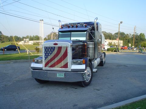 1966 International School Bus - A semi-truck is parked outside, a prominent American flag design on its grille and a visible license plate.