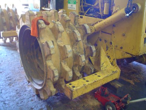 1966 International School Bus - Close-up of a heavy-duty compactor roller, showing its toothed surface and hydraulic components.