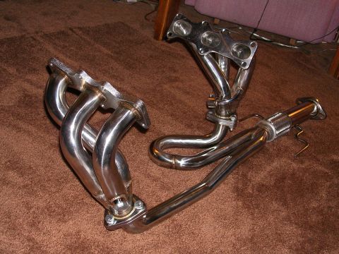 1996 Ford Probe - Aftermarket exhaust headers and pipe components are displayed on a carpeted floor.