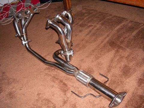 1996 Ford Probe - This is a set of aftermarket exhaust headers and a section of exhaust pipe, likely for a car. The parts are made of polished metal and are…