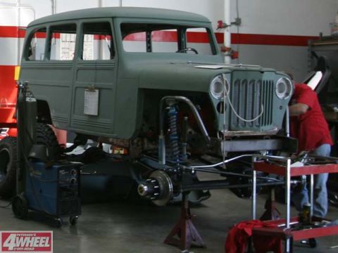1985 Ford Bronco - A green Jeep Willys Wagon is shown from the front during a restoration project, with its chassis and suspension components visible.