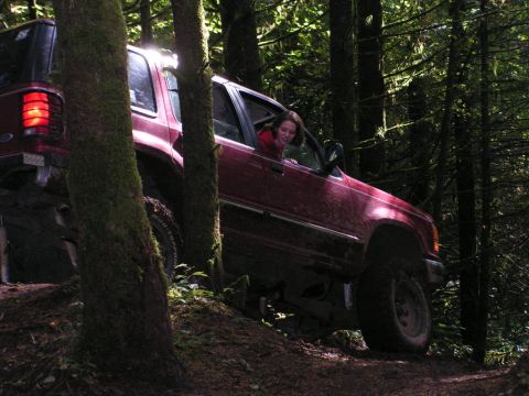 1991 Ford Explorer - A red 1991 Ford Explorer navigates a wooded trail with a driver looking out the window.