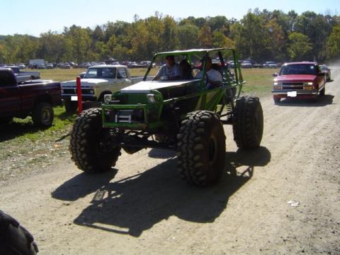 1979 Ford Bronco - A custom-built off-road buggy navigates a dusty track during an event, with other vehicles visible in the background.