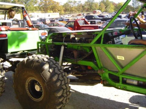 1979 Ford Bronco - Custom off-road buggy with massive tires is parked next to another vehicle at an event.