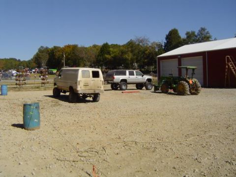 1979 Ford Bronco - Three vehicles are parked on a gravel lot outside a red building with a white roof.