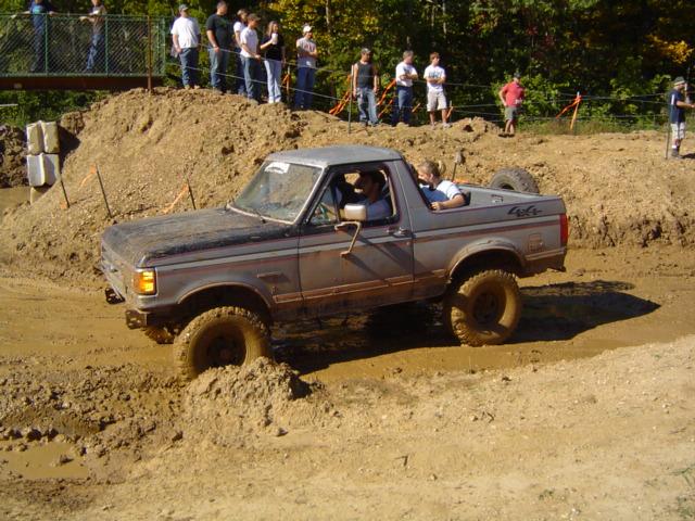 Gray Ford Bronco with 4x4 decal navigating a muddy off-road course