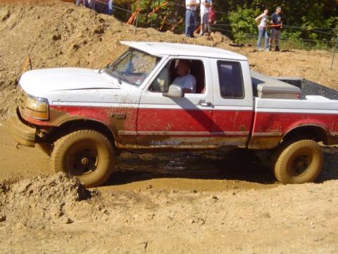 1979 Ford Bronco - Pickup truck navigates a muddy obstacle course during an event.