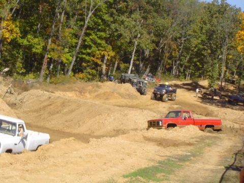 1979 Ford Bronco - Trucks navigate a challenging off-road course during a sunny day event.