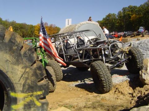 1979 Ford Bronco - Custom off-road buggy with an American flag flies during an event. Multiple vehicles are present.
