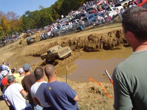 1979 Ford Bronco - A crowd watches as a truck navigates a muddy obstacle course during an event.