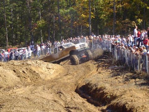 1979 Ford Bronco - A modified truck navigates a muddy course with spectators observing the event.