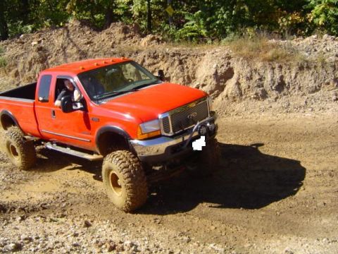 1979 Ford Bronco - This orange Ford F-250 Super Duty pickup truck is equipped for off-road driving on a dirt path.