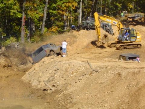 1979 Ford Bronco - Multiple off-road vehicles navigate a challenging mud pit, with an excavator present on the scene.