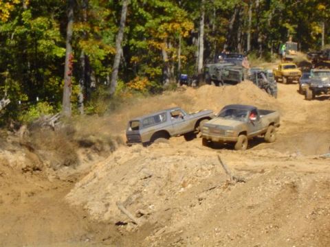 1979 Ford Bronco - Multiple off-road vehicles navigate a muddy terrain during an event.