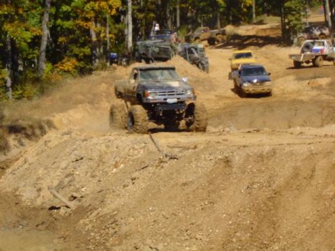 1979 Ford Bronco - Multiple off-road vehicles navigate a muddy, hilly terrain during an event.