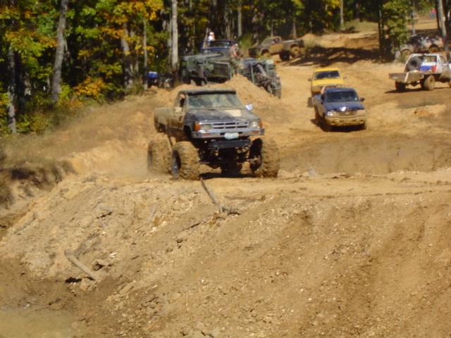 Truck climbing dirt hill with large tires. Supermotors logo visible