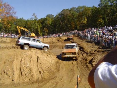 1979 Ford Bronco - Vehicles tackle a challenging mud course during an event, with a large crowd observing the action.