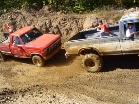 1979 Ford Bronco - Two pickup trucks are stuck in the mud during an off-road event.