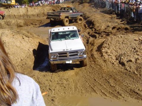 1979 Ford Bronco - A GMC pickup navigates a muddy off-road course during an event.