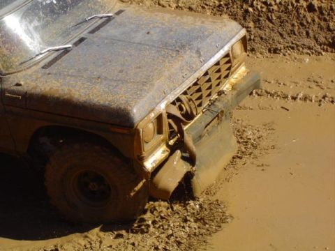 1979 Ford Bronco - This truck is deeply stuck in thick mud, with only its front end visible.